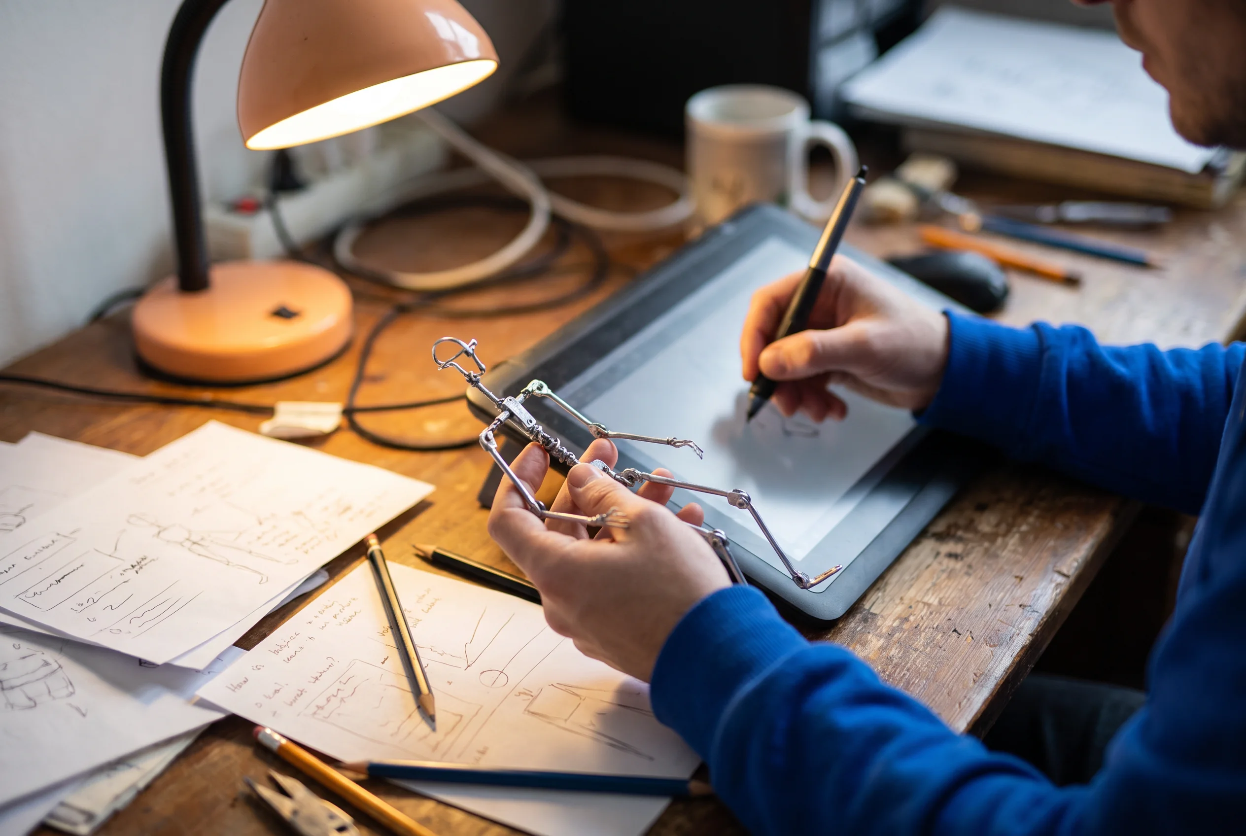 Animator using a stylus while holding a wire puppet armature